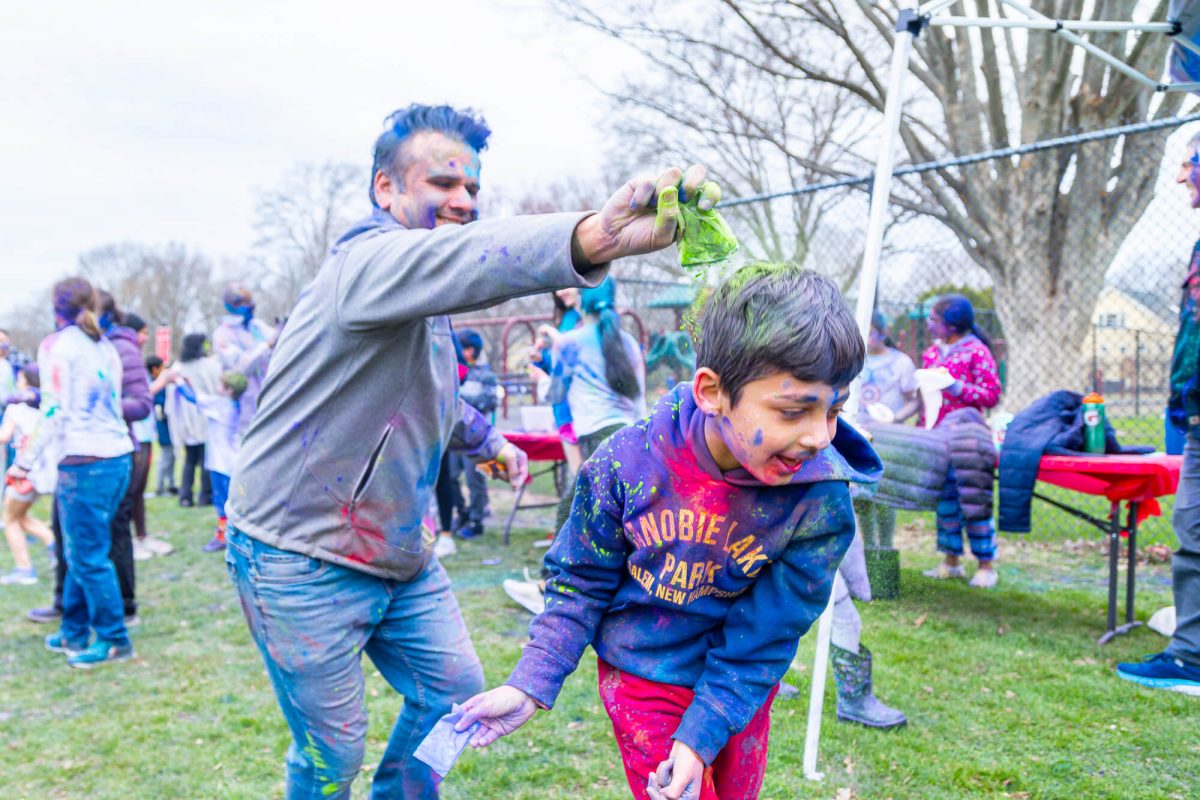 Pankaj Arora decorates his son, Ansh, with a packet of brilliant green powder. Photo: Stephen Beyer/The Concord Bridge